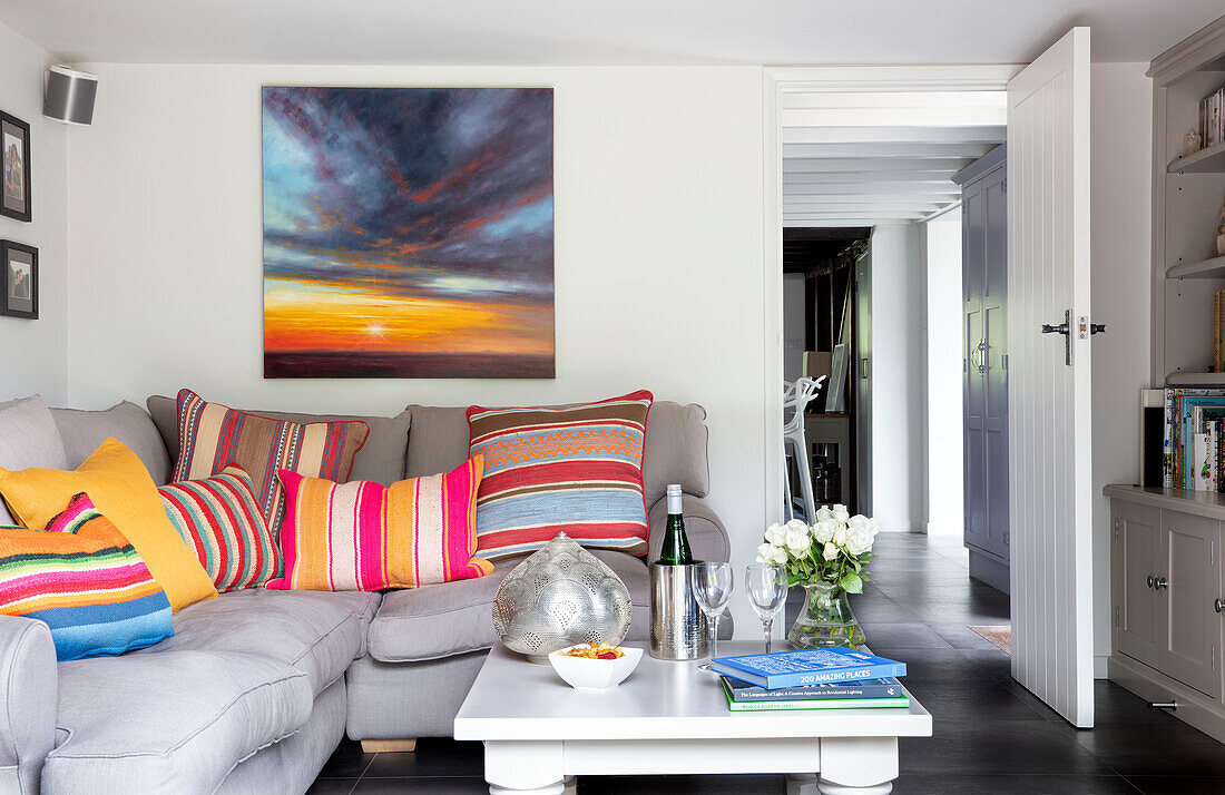Corner sofa with brightly striped cushions and artwork Surrey UK