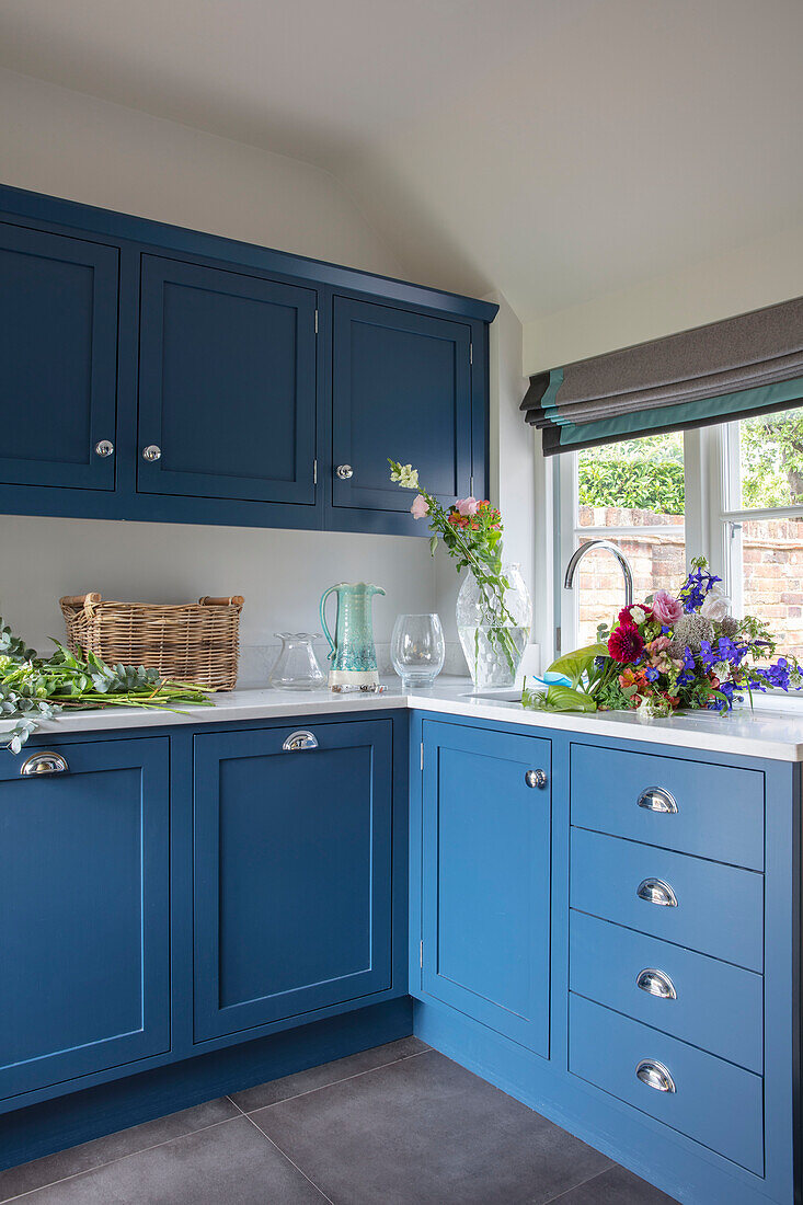 Blaue Einbauküche mit Schnittblumen im Spülbecken Surrey UK