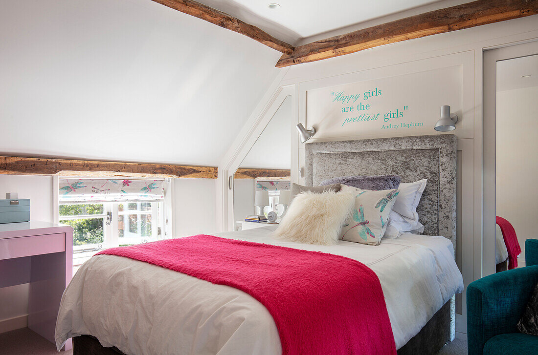 Rote Decke auf dem Bett im Jugendzimmer eines Mädchens in Surrey UK