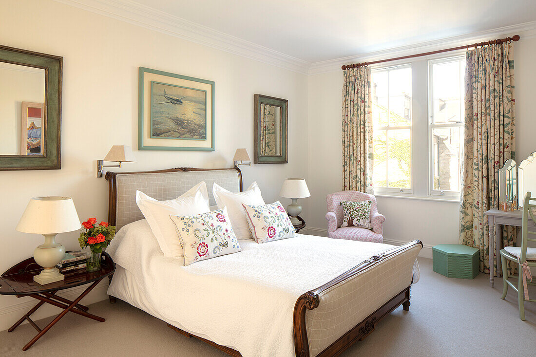Doppelbett mit geblümten Vorhängen und Kissen in einem Haus im Südwesten Londons UK