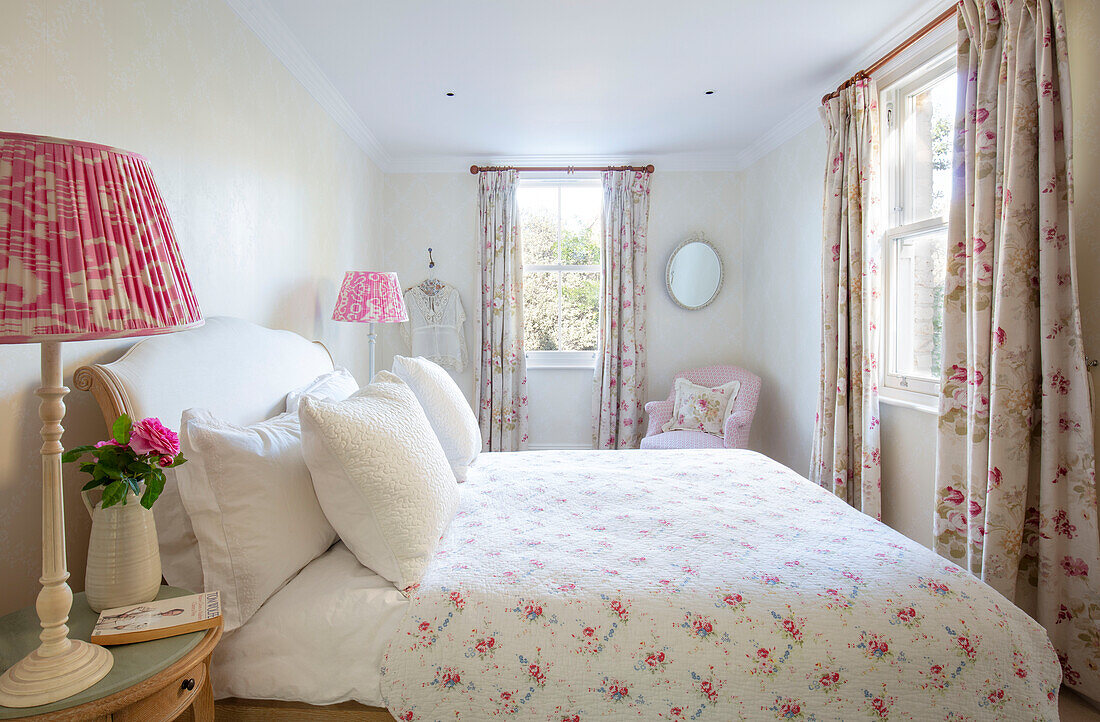 Floral bed cover and curtains with pink lamps in Southwest London home UK