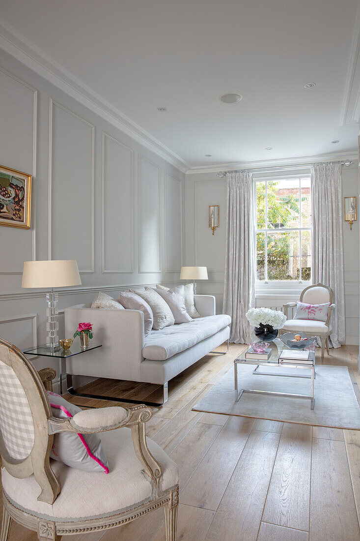 Paar cremefarbene Sessel mit weißem Sofa in getäfeltem Wohnzimmer London UK