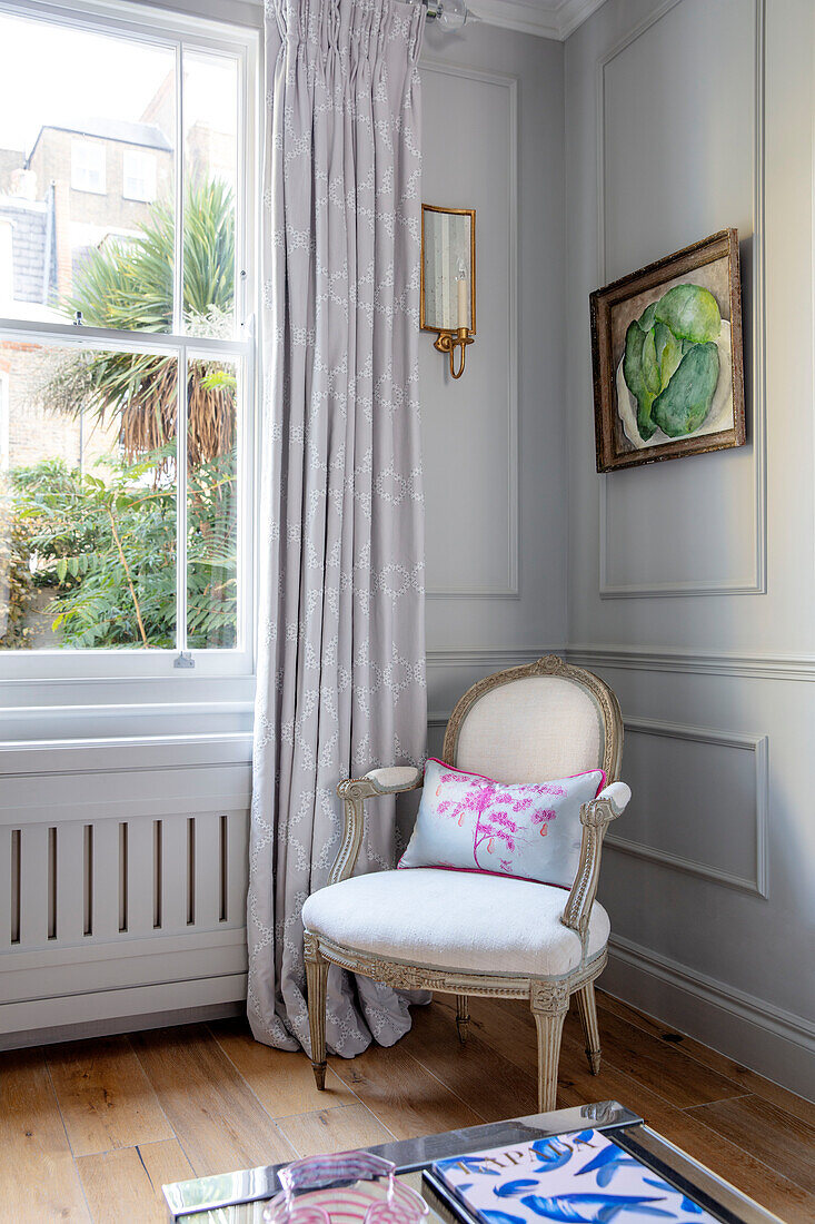 Armchair in window of panelled living room London UK