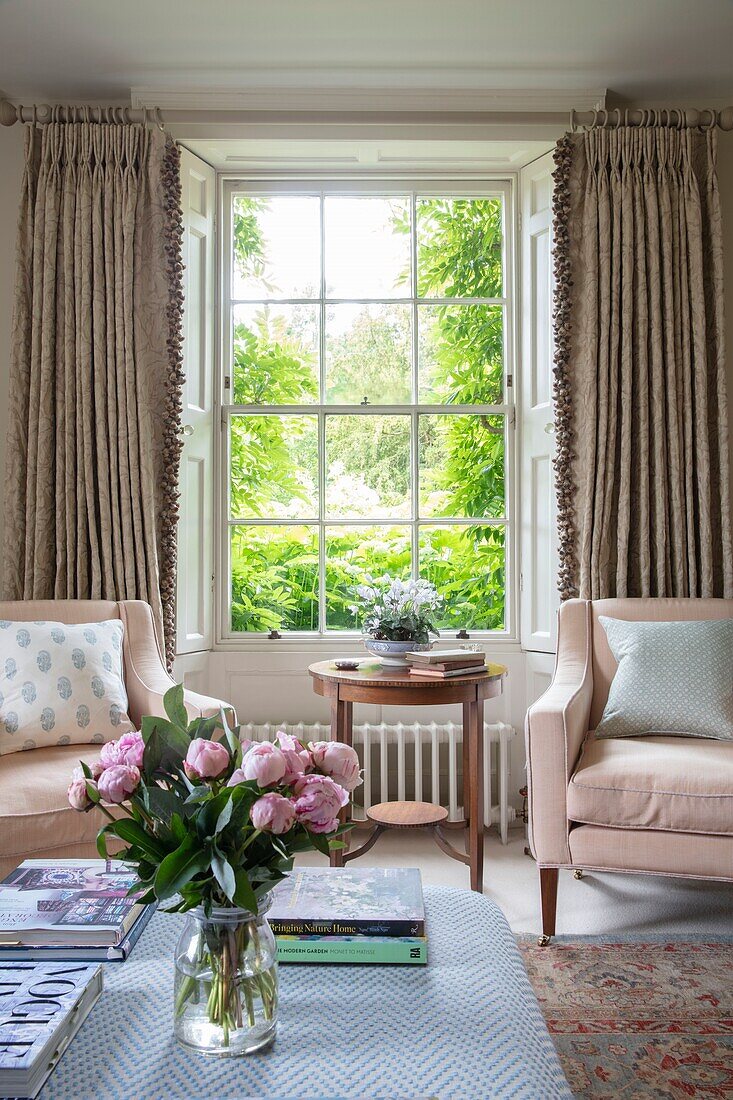 Elegantes Wohnzimmer mit frischen Schnittblumen und hellrosa und cremefarbenen Möbeln Hampshire UK