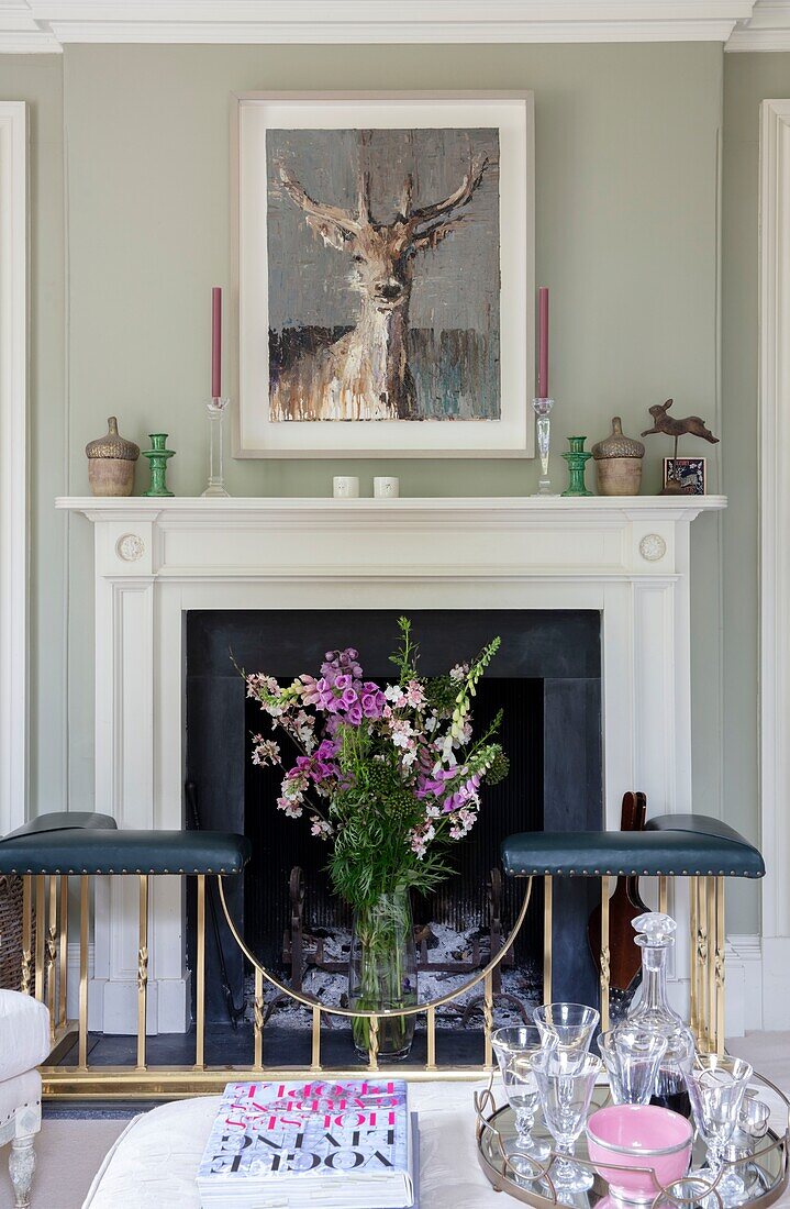 Fireplace detail with fresh cut flowers in living room of Hampshire UK