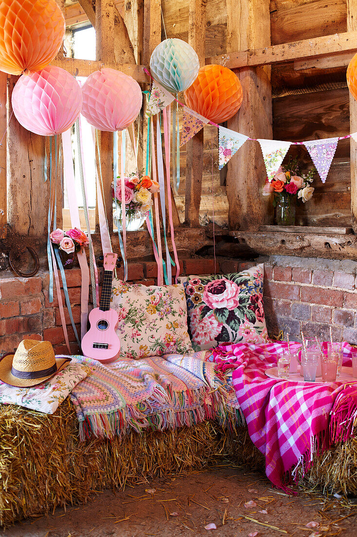 Ukulele and floral cushions on haybale seating with bunting in late summer