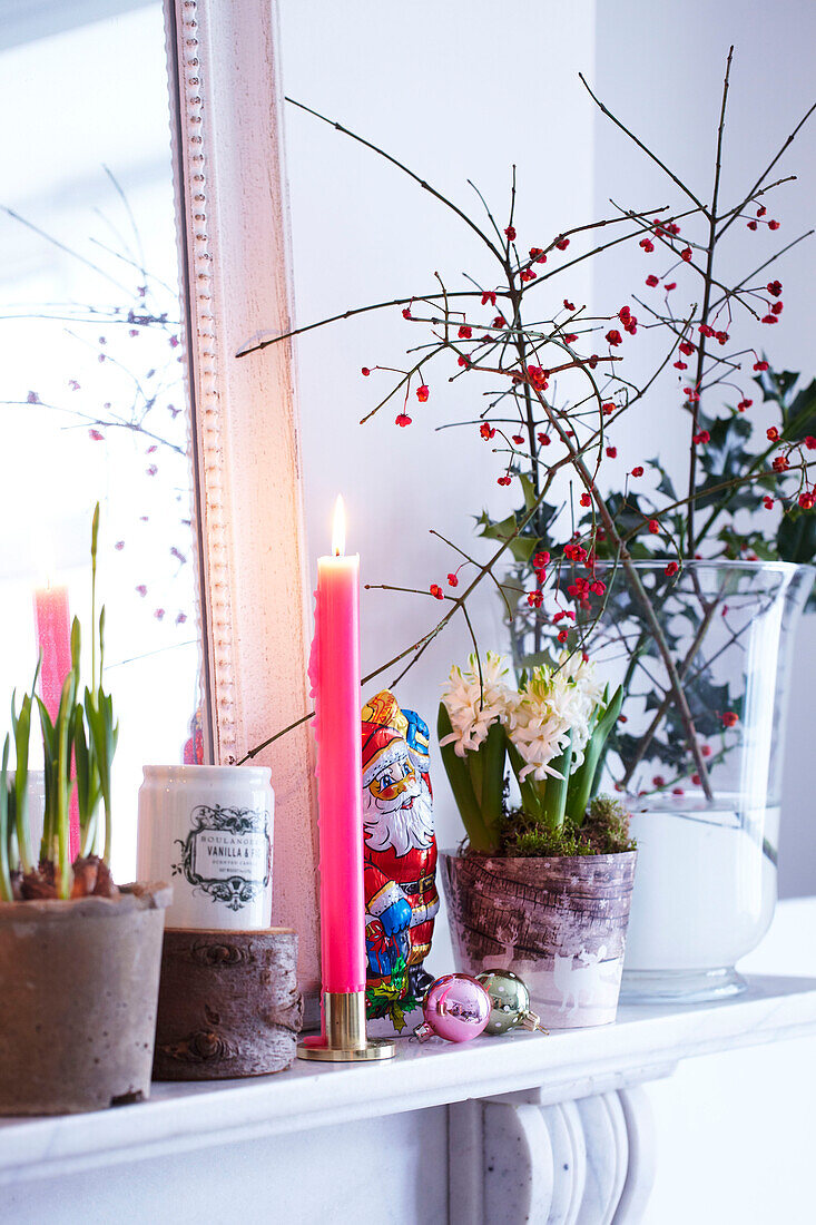Christmas Mantlepiece Detail mit rosa Kerze und Hyazinthen und Beeren