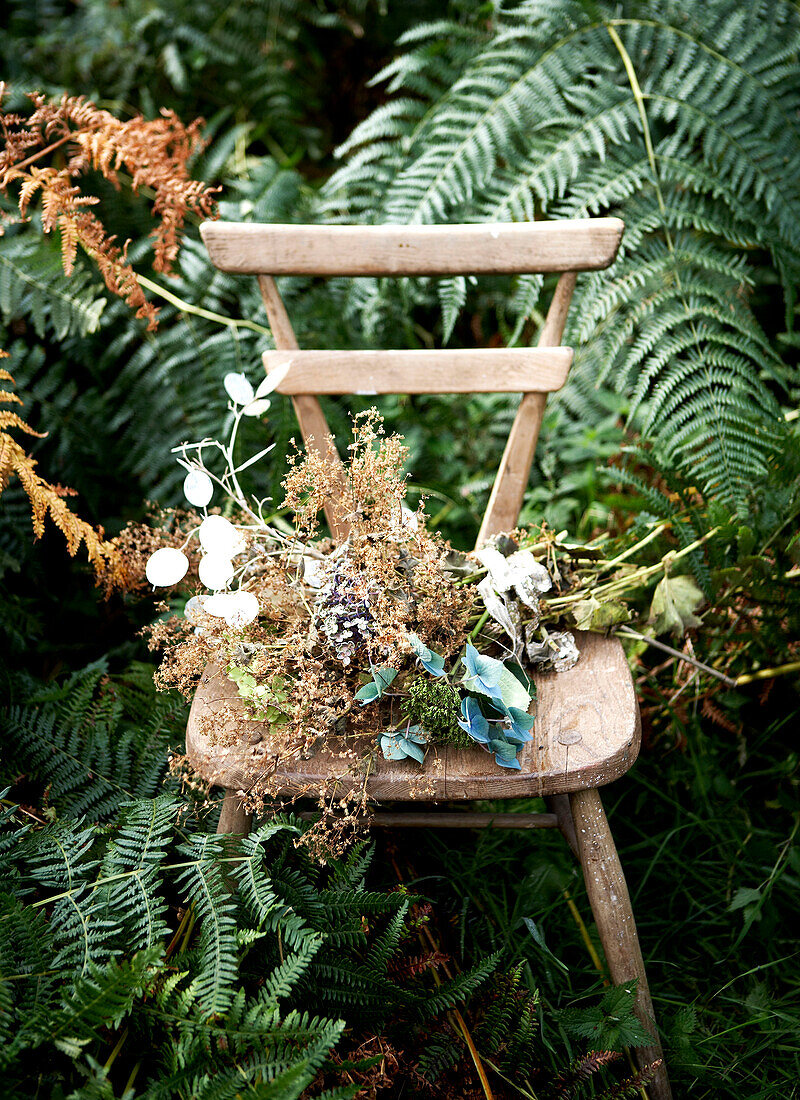 Getrocknete Blumen auf Holzstuhl in Farnlandschaft Isle of Wight, UK