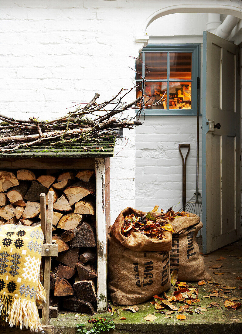 Anzündholz und Brennholz mit Säcken voller Laub in einem Holzschuppen auf der Isle of Wight, Großbritannien