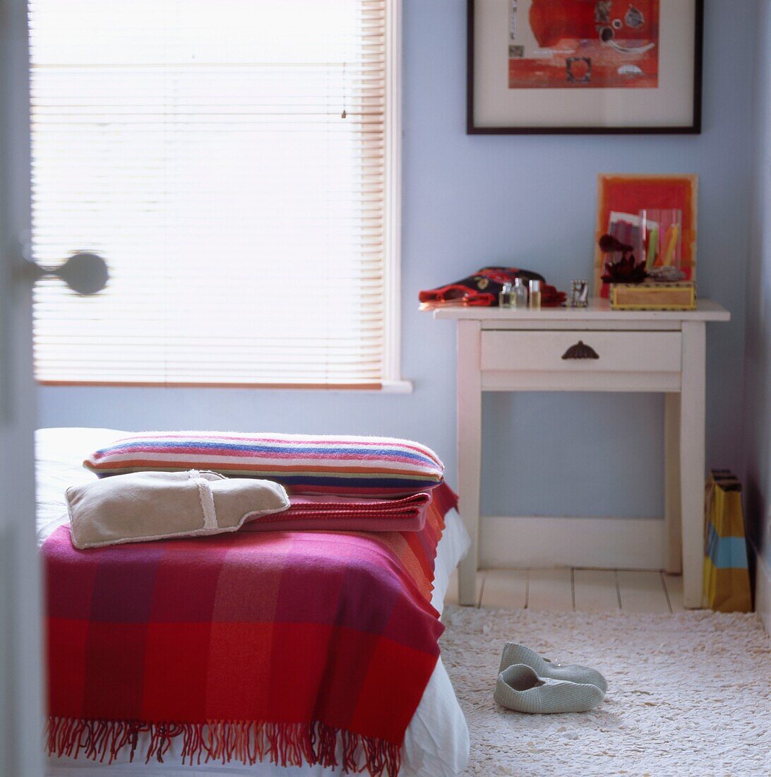 Pastellblaues Schlafzimmer mit bunten Decken, Wärmflasche und Hausschuhen aus Filz