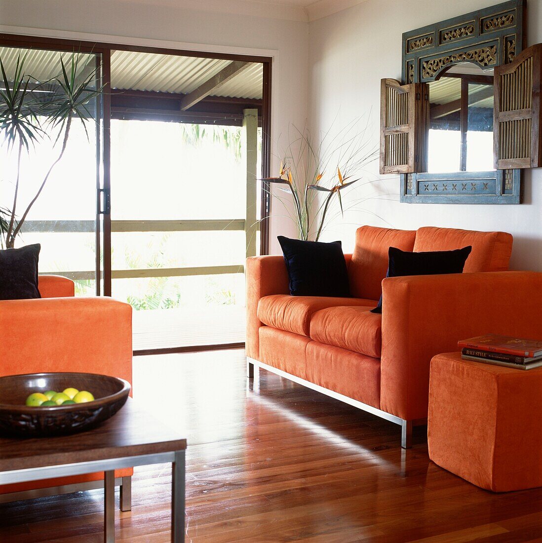 Orangefarbene Wildledersofas in einem Wohnzimmer mit Terrassentüren, die zur Sonnenterrasse führen