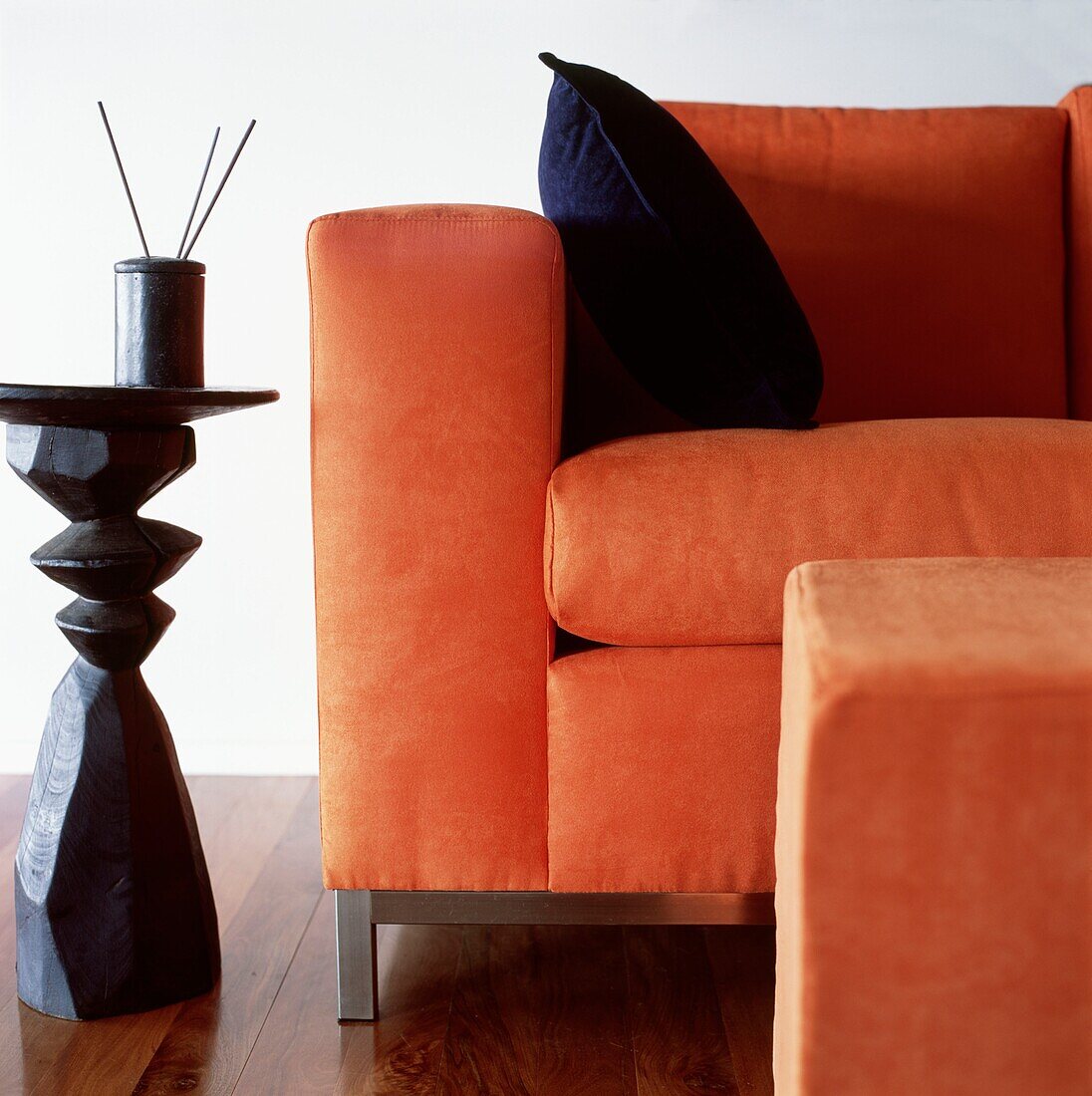 Orange suede sofa with foot stool and side table