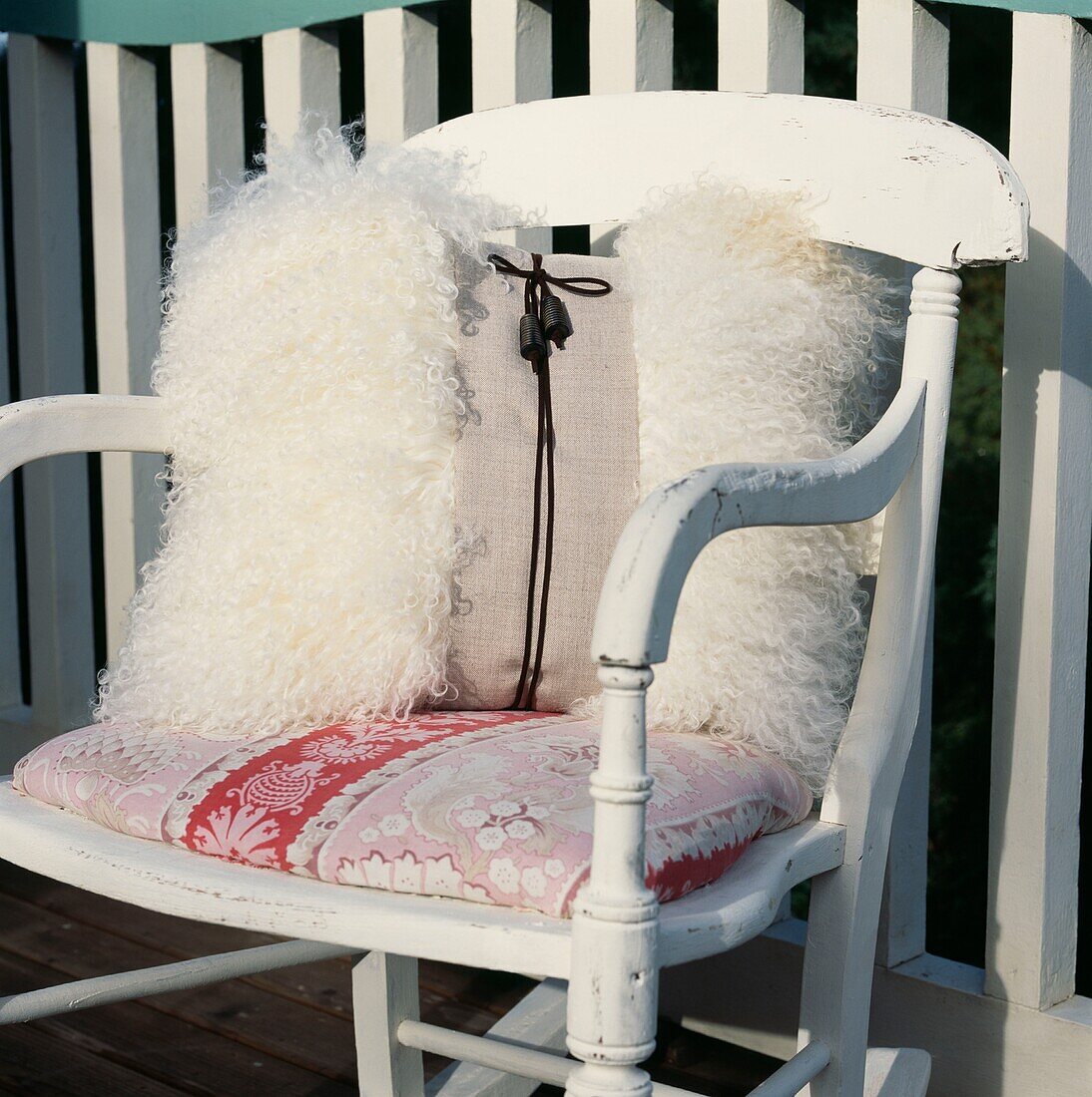 Wooden painted rocking chair on a balcony with fake fur cushion