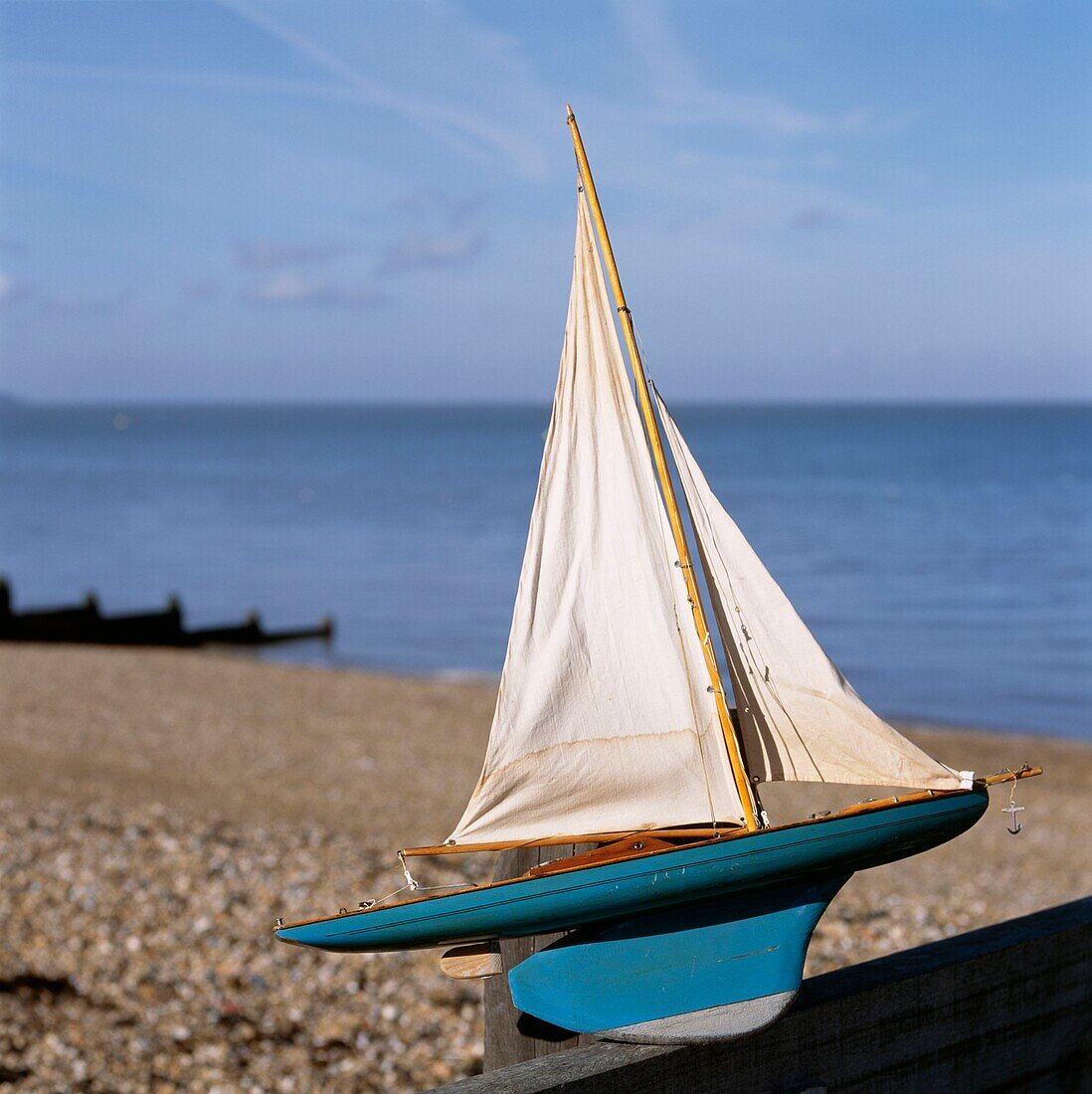 Vintage-Spielzeug-Segelboot auf einem Kiesstrand
