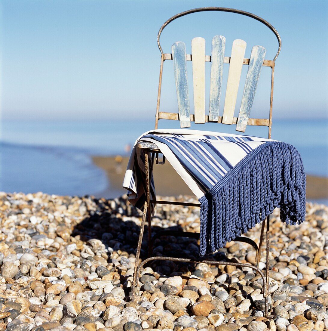 Stuhl im Vintage-Stil mit Decke an einem Einzelstrand