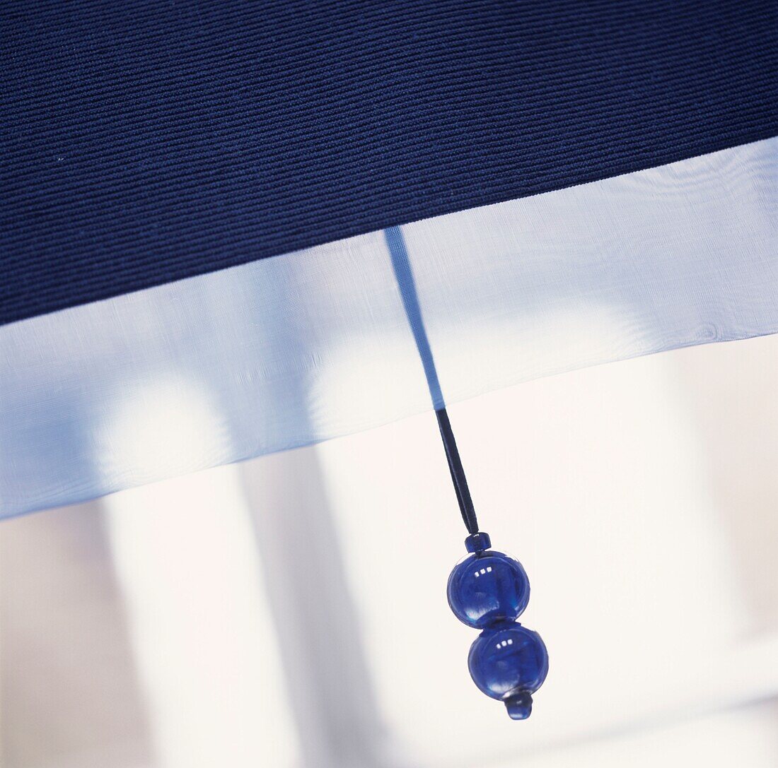 Blauer Perlenzug an einem Fensterrollo