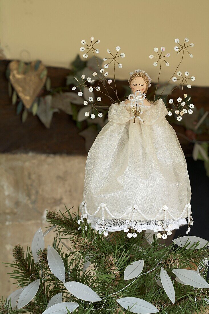 A Christmas decoration fairy sitting on top of a tree