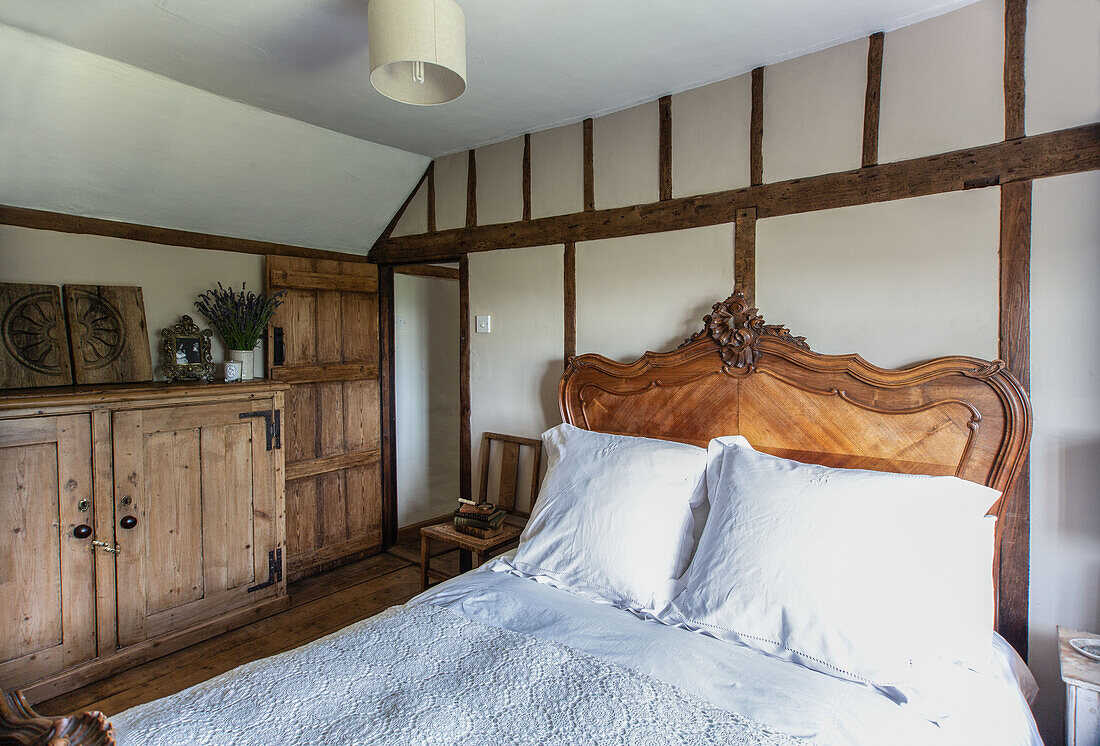 Cottage bedroom with reclaimed pine furntiture and carved wooden headboard