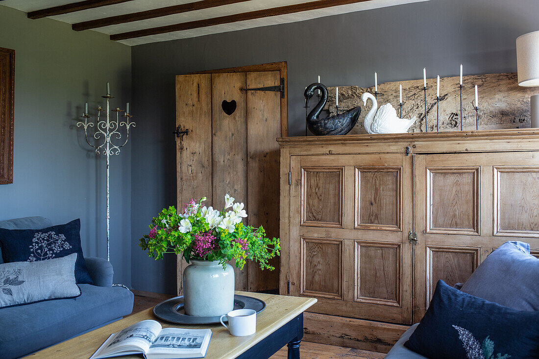Wohnzimmer mit antikem Kiefernschrank und schwarz-weißen Keramikschwänen