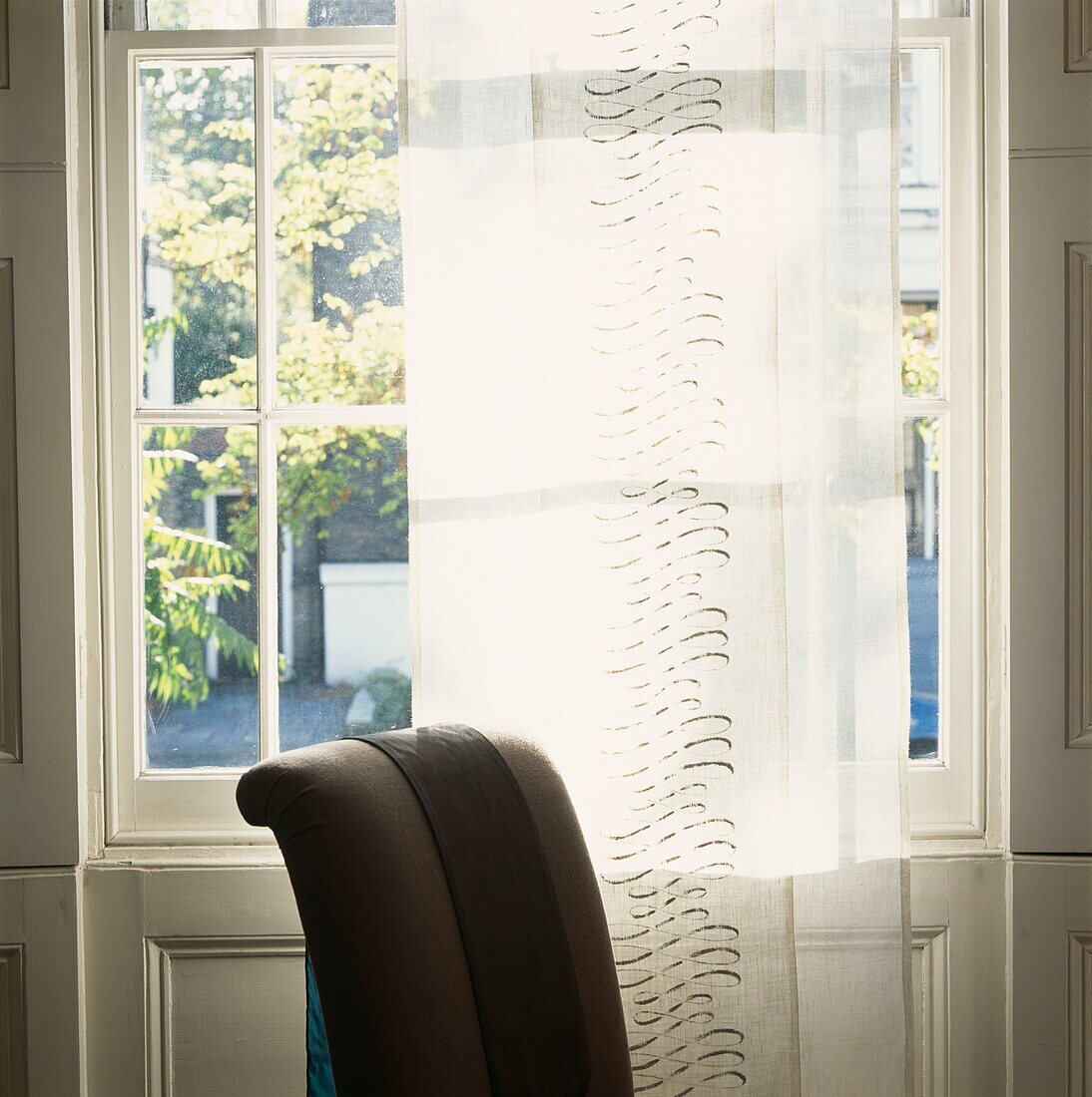 Voile curtain strip at a Georgian window with chair back