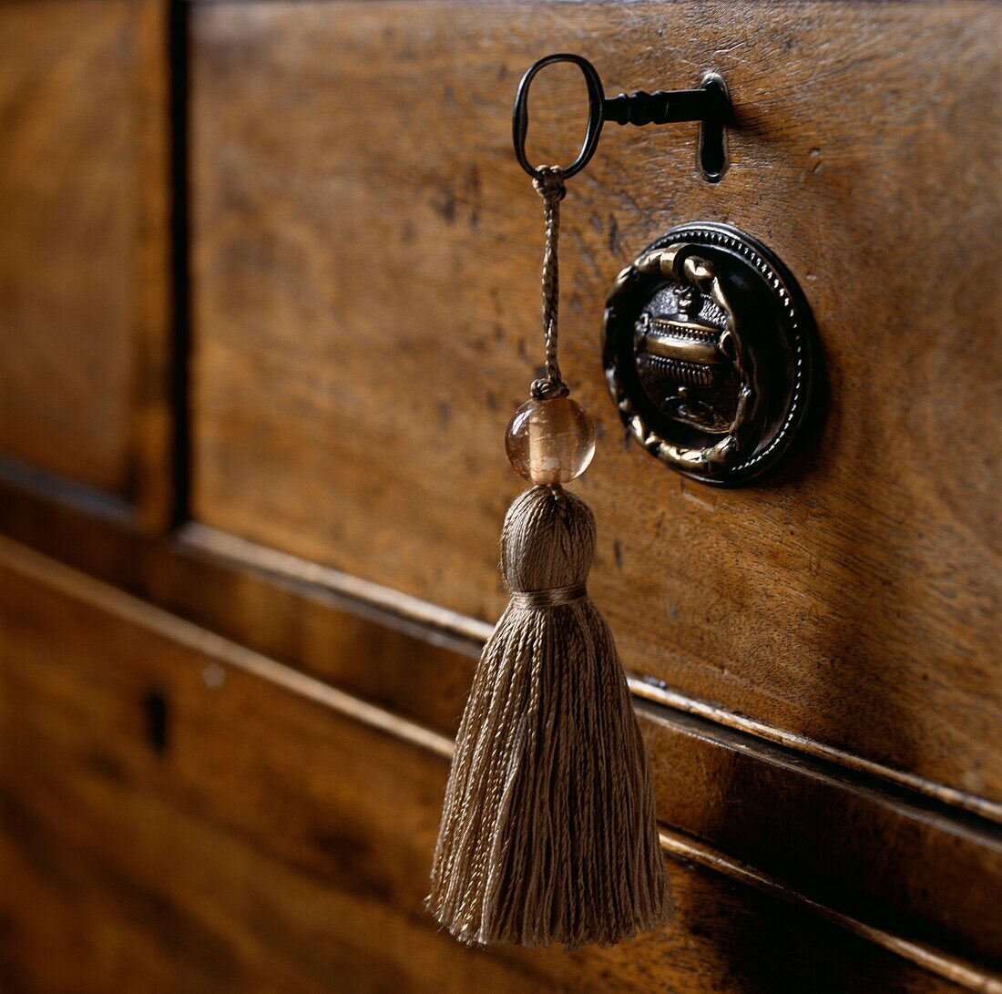 Gold coloured tassel attached to a vintage key in a wooden chest of draws