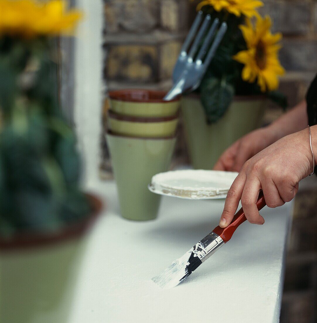 Person painting a window sill white