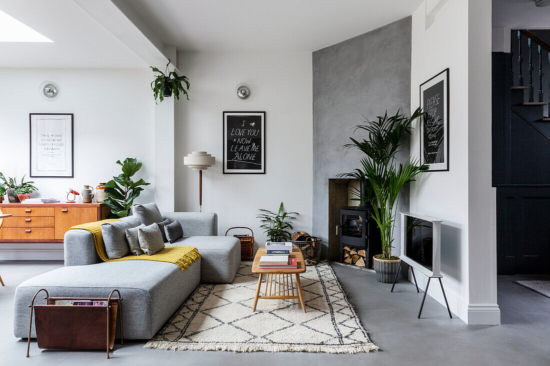 Modern eingerichtetes Wohnzimmer mit hellgrauem Sofa, Kamin und zweifarbiger Wandgestaltung