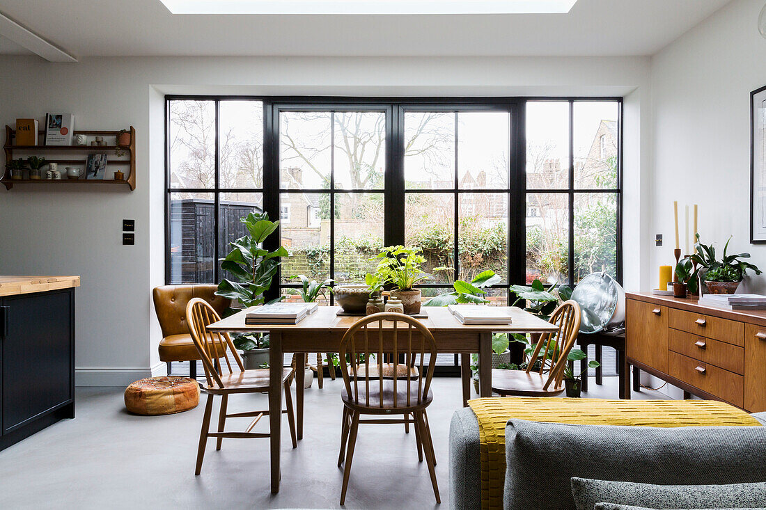 Bright dining area with wooden table, plants and vintage furniture