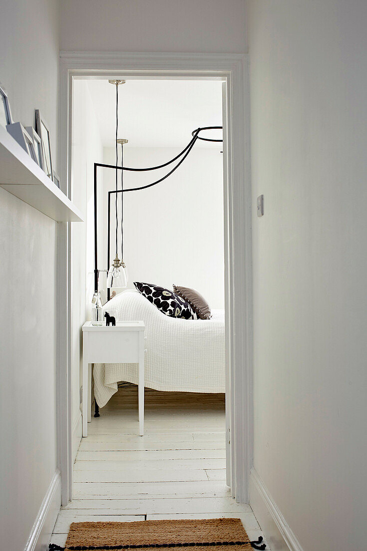 View into a white bedroom with a canopy queen bed