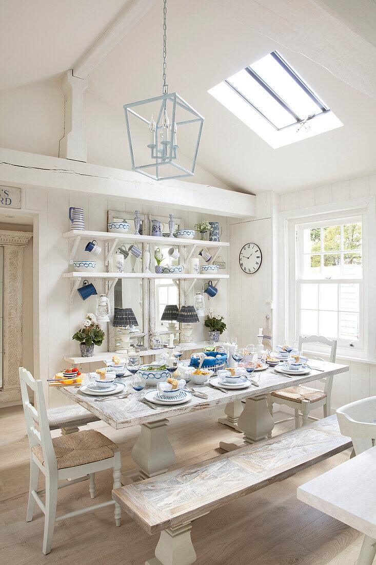 Country-style dining room with set table, shelves and skylight