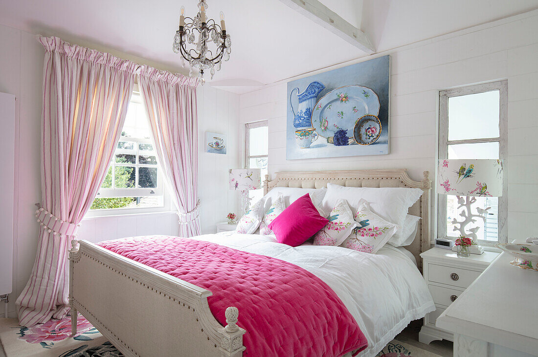 Country-style bedroom with pink bedspread, chandelier and picture