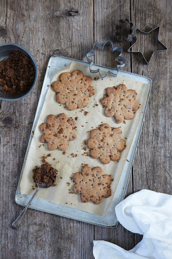 Baked biscuits on a baking tray with cookie cutters and leftover dough