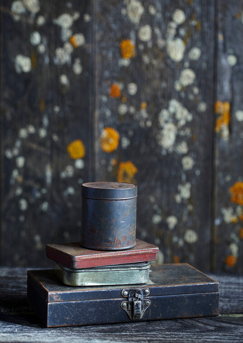 Stack of old metal boxes in front of weathered wooden boards