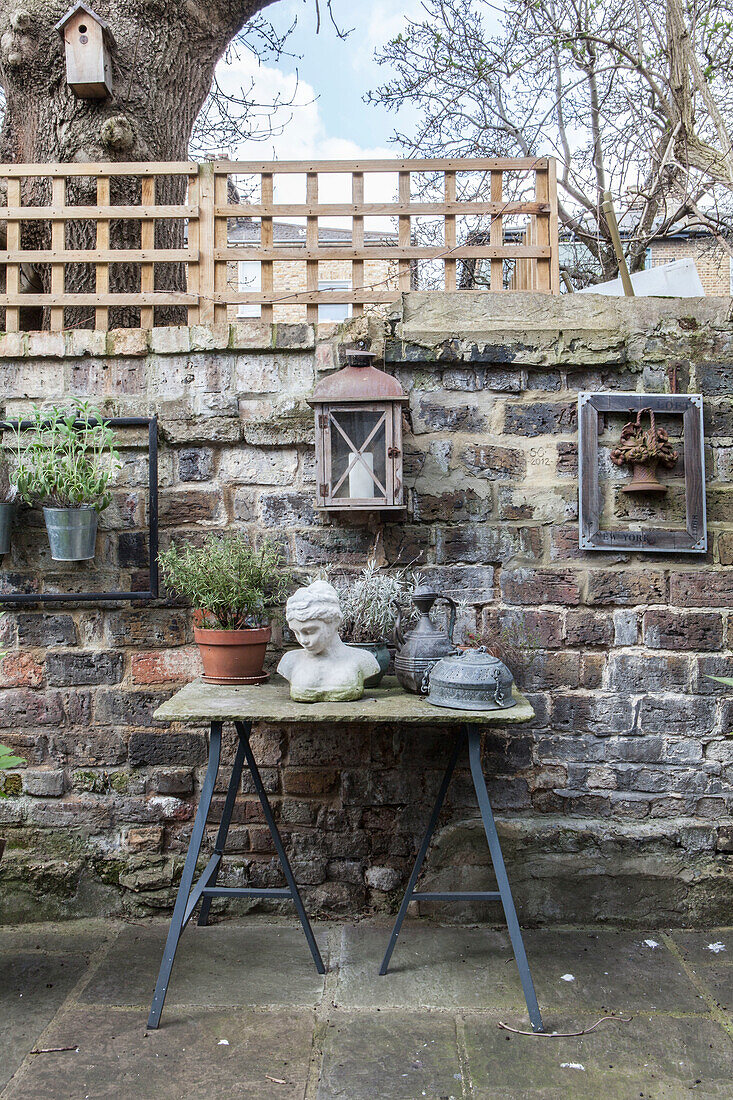 Garden ornaments on table against vintage brick wall