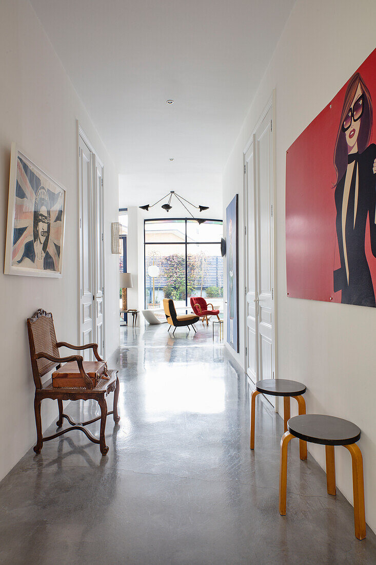 Weißer Flur mit poliertem Betonboden, Sitzmöbeln und moderner Kunst