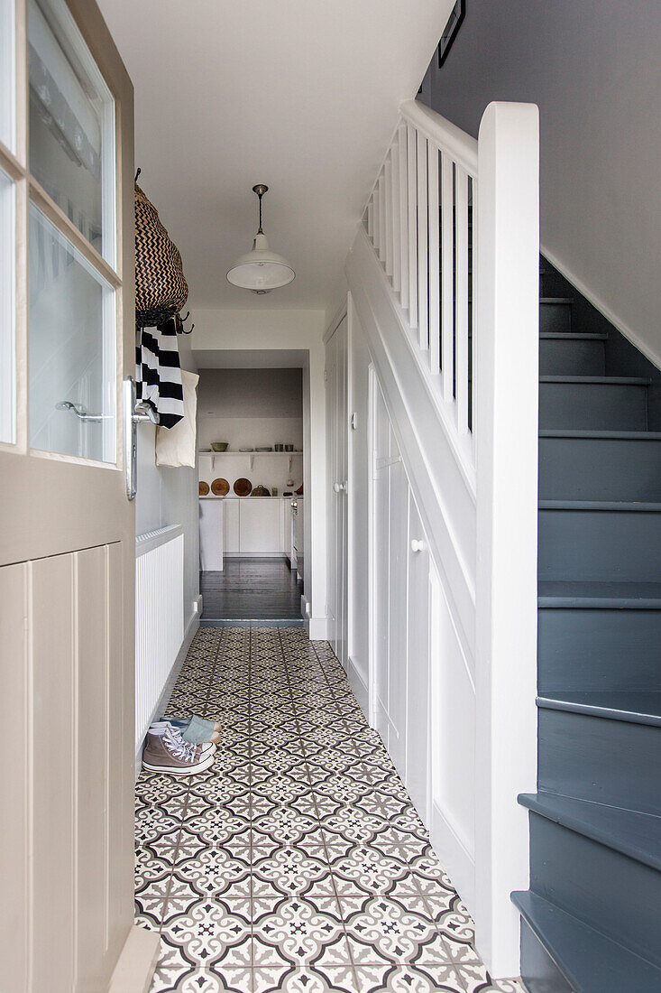 Hallway with patterned floor tiles and blue staircase in a house