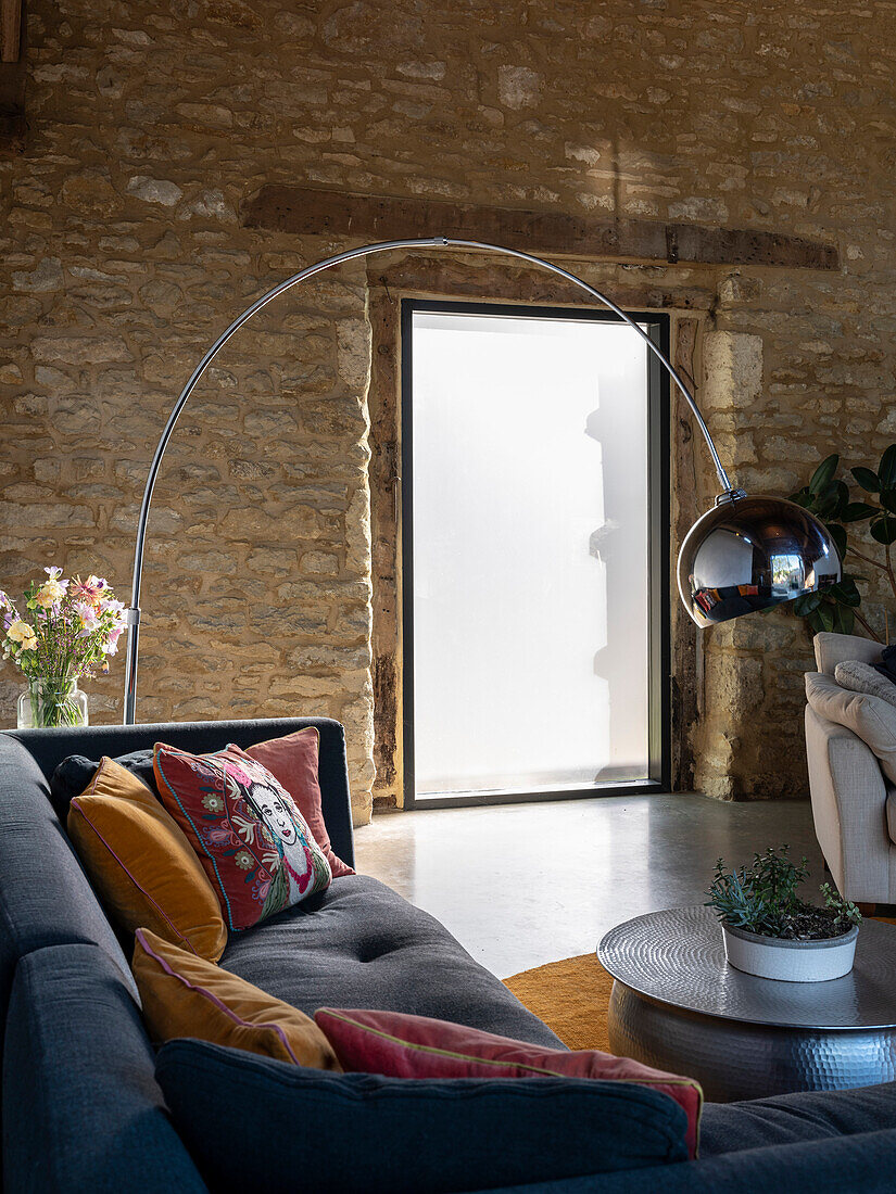 Detail of sitting area with large floor lamp and large window in a former barn