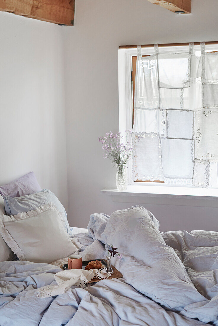 Schlafzimmer mit DIY-Gardine aus Spitzendeckchen und Kissen mit Spitze