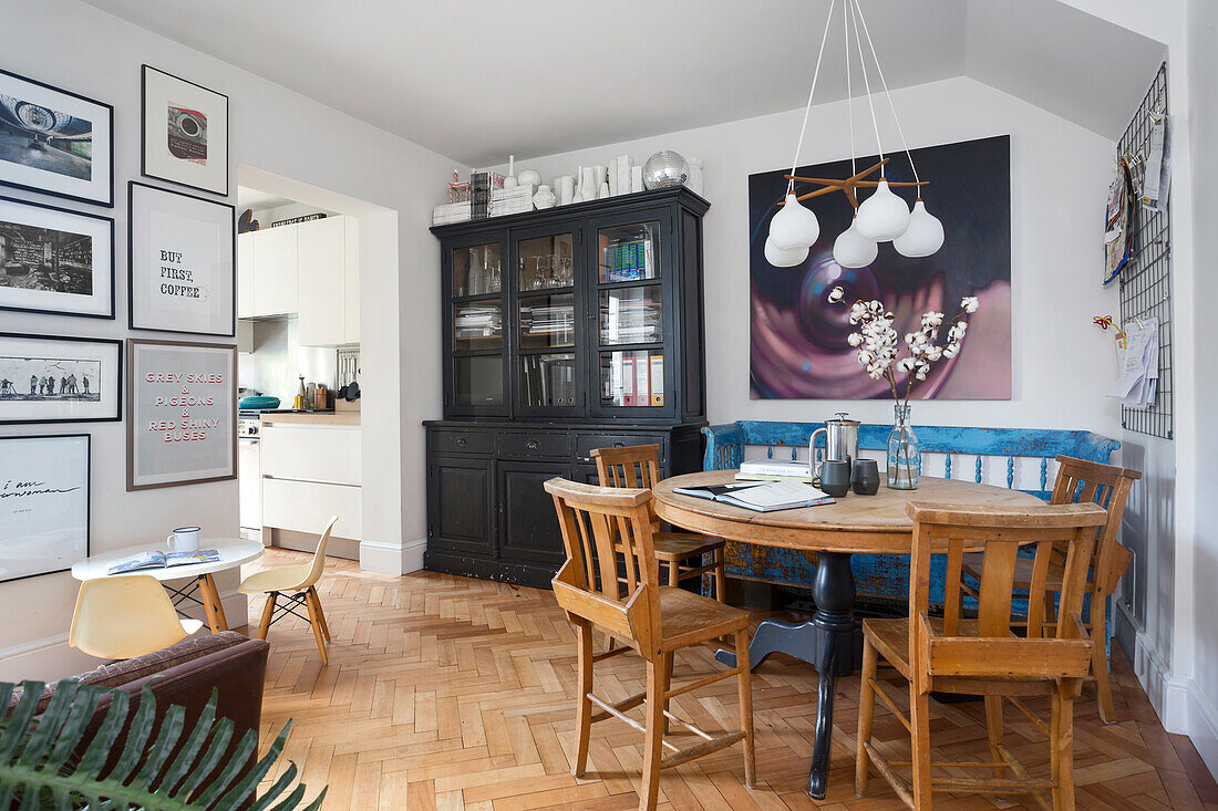 Dining area with round wooden table and chairs, picture wall and display cabinet