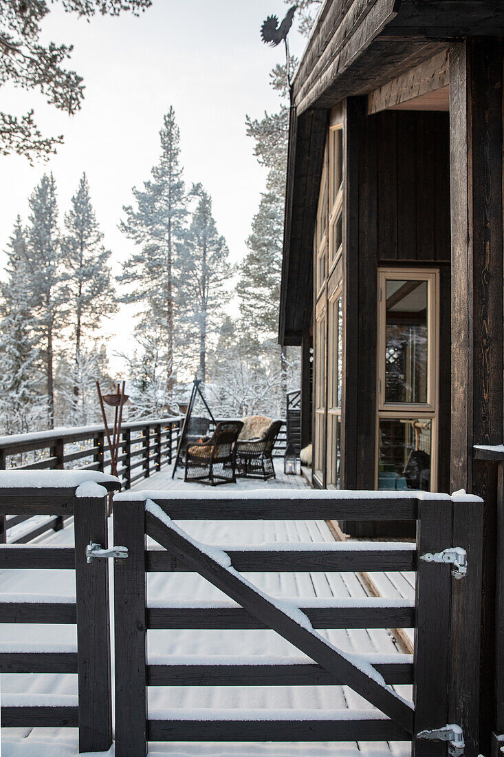 Wooden terrace with seating in a snowy setting with trees