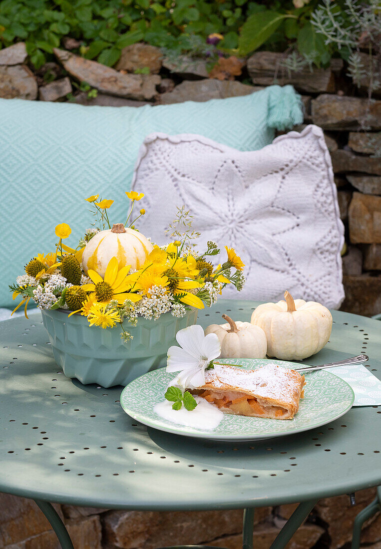 Autumnal decoration with yellow flowers and pumpkins on table in the garden