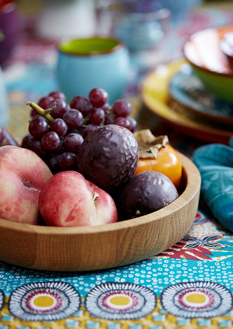 Fruit bowl with grapes and peaches on a colourful patterned tablecloth