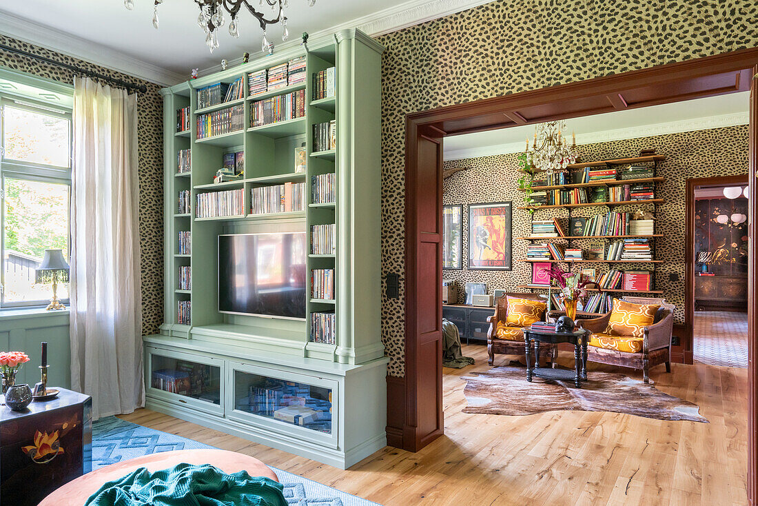 Wohnzimmer mit Bücherregal, Parkettboden und Leopardenmuster-Tapete