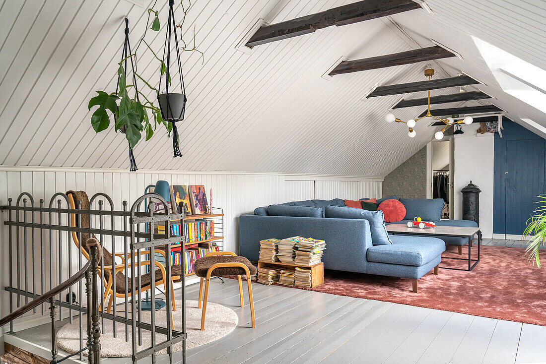 Attic living room with blue sofa, bookshelf and plants