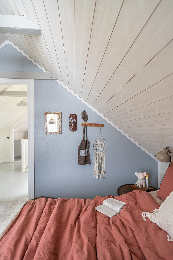 Attic bedroom with wall decoration and open book on bed