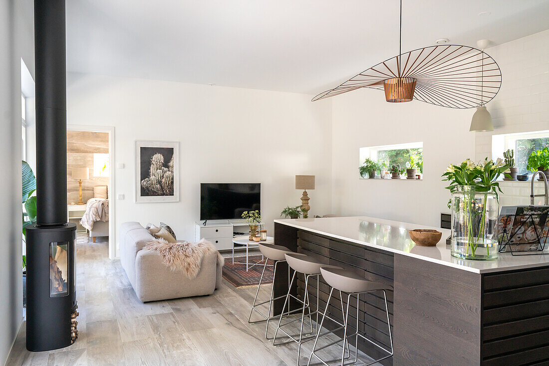 Modern kitchen with bar stools and fireplace in open-plan living area