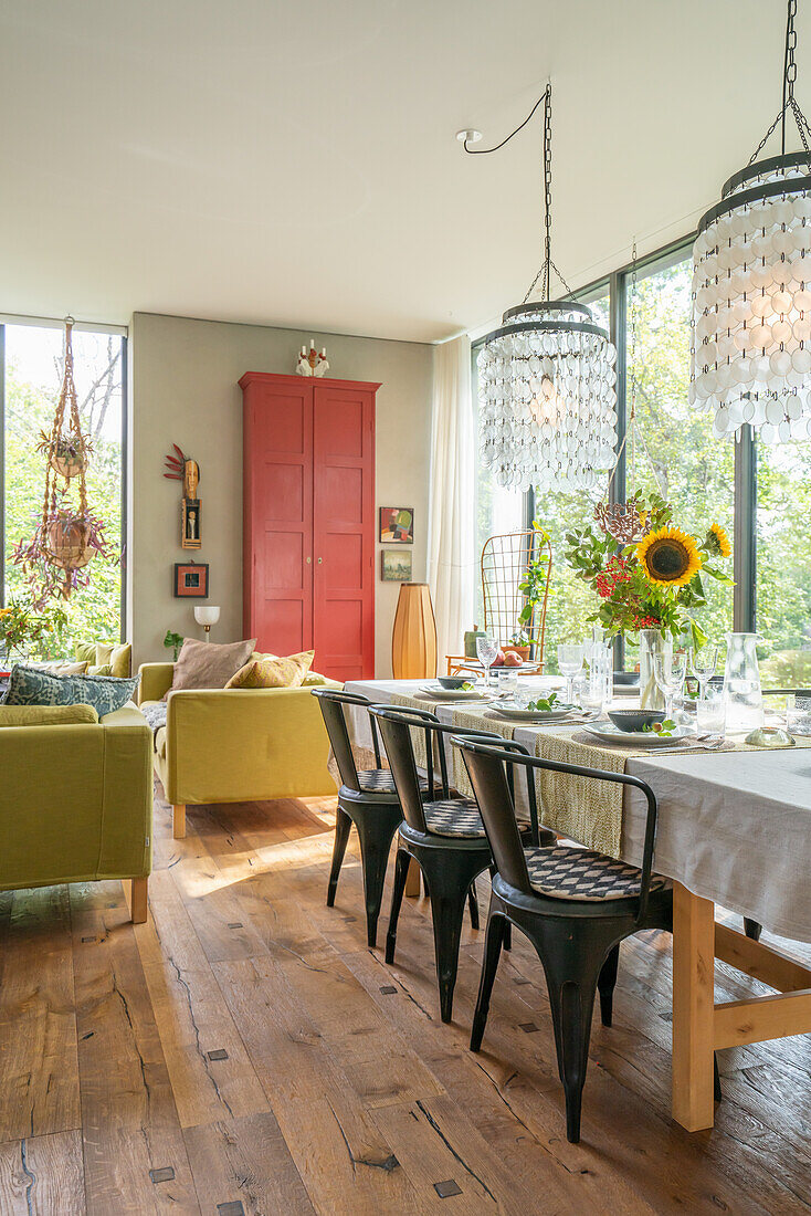 Set dining table with bouquet of flowers, pendant lights and red cupboard