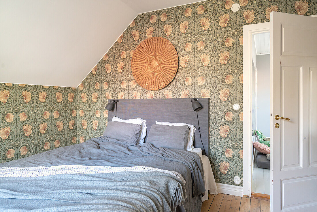 Bedroom with patterned wallpaper and rattan decoration above the bed