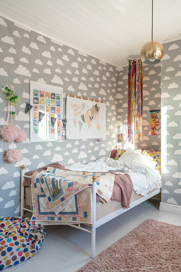 Kinderzimmer mit Wolkentapete und buntem Quilt auf dem Bett