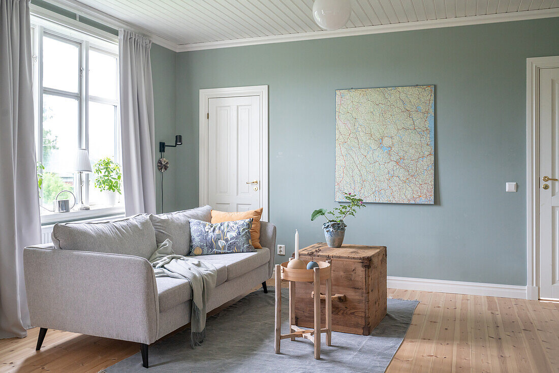 Living room with grey sofa, wall map and wooden furniture